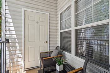 the front porch of a home with a white door and chairs